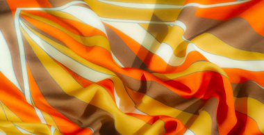 Pürüzsüz kıvrımlı, turuncu, sarı ve kahverengi kumaşlı. Canlı, sıcak renkler büyüleyici bir enerjiyle modern, şık bir tekstil deseni yaratır.