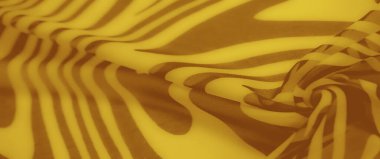 Kıvrımlı kahverengi soyut desenli canlı sarı kumaş bulanıklığı. Katlar dinamik hareket yaratır, cesur ve oyuncu tasarımı geliştirir. Tekstil ve model meraklıları için ideal.