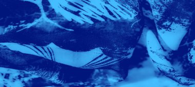 Karmaşık dokular ve desenler içeren mavi bir kumaşın bulanıklığı soyut doğal formlar, ince ışık ve koyu zıtlıklar..