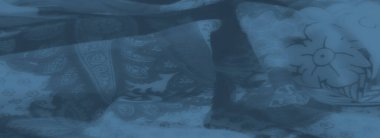 Karmaşık çiçekli ve desenli serin mavi tonlarda detaylı bir kumaş dokusu. Katlar ve katmanlar kompozisyona derinlik ve zarafet ekler.