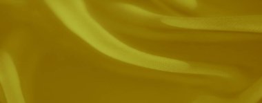 Hassas dokusu ve zarif kıvrımları olan akışkan sarı kumaş bulanıklığı. Işık, yumuşak kıvrımlarını ve lüksünü artırmak için pürüzsüz malzemeler üzerinde oynar..