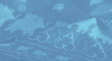 Karmaşık beyaz fil ve çiçek motifleriyle açık mavi bir kumaşın bulanık görüntüsü yumuşak ve sakinleştirici bir doku yaratır. Kumaşın ince kıvrımları ve zarif desenleri var..