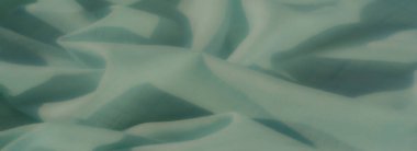 Nane yeşili kumaş zarif bir şekilde akar, yumuşak gölgelerin etkileşimini ve bu minimalist tasarımda doğal kıvrımları arttıran hassas bir şebeke deseni ile..