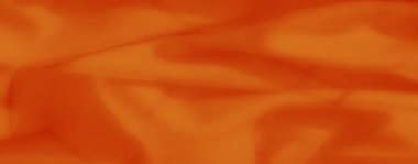 Karmaşık desenleri ve akan dokuları olan parlak turuncu kumaş bulanıklığı. Vurgulanan kıvrımlar kompozisyona derinlik ve sanatsal hareket ekler.