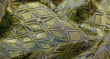 Metalik işlemeli desenli elmas desenli yeşil ve mavi kumaşın bulanık görüntüsü lüks ve çetrefilli bir görünüm yaratıyor..