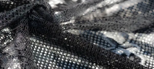 Bulanık siyah örgü kumaş parıltılı detaylar ve yumuşak şebeke dokuları sergiliyor. Gelişmiş ve rafine tekstil projeleri için ideal bir seçim..