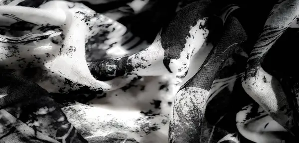 Yeşil röfleli siyah ve beyaz kumaşın bulanık detaylı görüntüsü, katmanlı desenleri ve zarif akış tarzını gözler önüne seriyor..