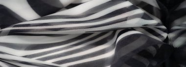 Katmanlı dalga desenli siyah beyaz kumaş bulanıklığı. Katlar hareket hissi katar ve parlak, sanatsal bir kompozisyon yaratır..