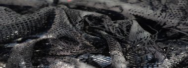 Karmaşık siyah dantel kumaşın bulanık yakın çekimi ışıl ışıl parlak ışıklar ve hassas dokular, zarafet ve sanatsal karmaşıklık hissi yaratıyor..