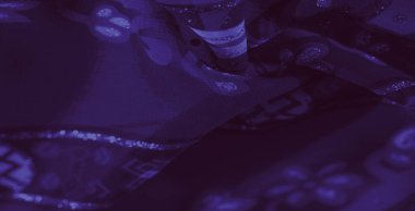 Görüntü, çarpıcı mor kumaş, karmaşık desenler ve yumuşak geometrik aksanlar, hassas iç içe geçmiş iplikler, derinlik ve doku ekliyor..