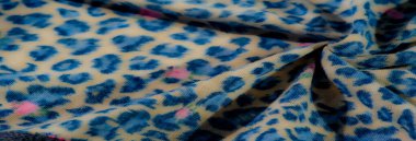 Bulanık mavi leopar desenli kumaş yumuşak pembe çiçek aksanıyla süslenmiş. Moda ve tasarım projeleri için mükemmel egzotik ve renkli bir doku yaratıyor..