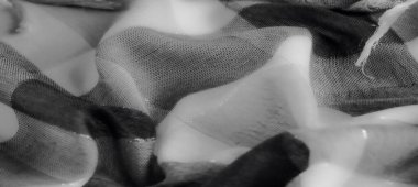 Pürüzsüz bir dokusu olan gri pullu kumaşın bulanık görüntüsü, ışığın dokumasının ve etkileşiminin karmaşık detaylarını gözler önüne sererek hassas bir estetik yaratıyor..