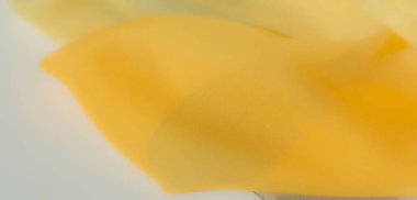 Bulanık, yumuşak kıvrımlı sarı kumaş ve yumuşak bir ışıkla aydınlatılmış pürüzsüz bir doku. Hassas desen ve sıcak renkler onu arka plan ve tekstil tasarımları için ideal kılıyor..