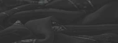 Karmaşık çiçekli ve geometrik tasarımlı bulanık katlanmış koyu kumaş, zamansız zarafet yayıyor ve yaratıcı tekstil projeleri için mükemmel bir zemin görevi görüyor..