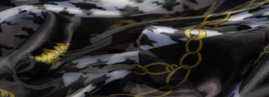 Şeffaf siyah ve beyaz tekstil ile altın zincir desenlerinin sanatsal karışımını bulanıklaştırarak, doku ve zarafetin kusursuz bir etkileşimini oluşturur..