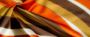 Ilık turuncu ve sarı renkli kahverengi çizgili parlak renkli kumaş bulanıklığı. Pürüzsüz dokusu ve karmaşık şablonu lüks ve zarafet hissi veriyor.