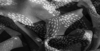 Bulanık, yumuşak ve pürüzsüz gri tonlu kumaş ince dokuları ve nazik kıvrımları var. Işığın ve gölgenin etkileşimi onun dingin ve zarif olduğunu vurgular..