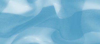 Yıpranmış dokuları ve dinamik kıvrımları olan parlak mavi kumaş bulanıklığı, tekstilin soyut formunda ışık ve gölgelerin çarpıcı bir etkileşimini temsil ediyor.