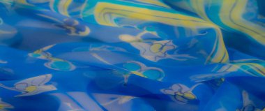 Rüzgarlı mavi kumaşı bulanıklaştırın. Karmaşık çiçekli desenler, canlı sarı ve kıtır beyaz. Yumuşak, akan kıvrımlar ve katıksız tasarım ferahlatıcı bir yaz estetiğini çağrıştırıyor..