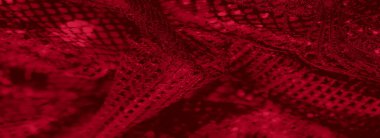 Görüntü - Karmaşık dantel desenleri ve hassas kıvrımları olan canlı kırmızı dokuma kumaşın yakın plan çekimi, ışık ve gölgelerin dinamik etkileşimini gösteriyor.