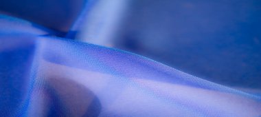 Pürüzsüz mavi kumaş kıvrımları, lüks bir doku ve zengin renk tonları yakalamak, arka plan kullanımı veya tekstil ilhamı için ideal.
