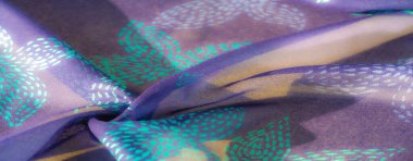 Canlı, şeffaf mor bir kumaşın bulanık yakın çekimi. Karmaşık deniz mavisi ve turkuaz nokta desenleri var. Işık, kıvrımlarda yumuşak, ruhani bir parıltı oluşturarak filtreler..