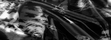 Görüntü: Geometrik şekiller ve zincirler içeren, geleneksel ve modern stilleri cesur, çarpıcı bir doku ve yansıtıcı gölgelerle harmanlayan gri pullu bir kumaş.