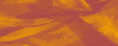 Görüntü, dokulu turuncu kumaş ve hassas desenler sıcaklık ve karmaşıklık yayar. Işık yumuşak kıvrımları nazikçe vurgular, onu dekor veya moda uygulamaları için ideal hale getirir