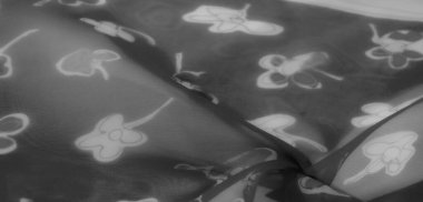 Bulanık siyah beyaz fotoğraf güzel kumaş üzerindeki çiçek motiflerinin güzelliğini yakalıyor. Karmaşık tasarım ve yumuşak kıvrımlar dokuya derinlik ve karmaşıklık ekler..
