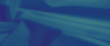 Görüntü. Yumuşak kıvrımları ve gölgeleri olan dokulu mavi bir kumaş, sakin ve sanatsal bir ortam yaratıyor. Monokromatik tonlar minimalist zarafetine ekleniyor..