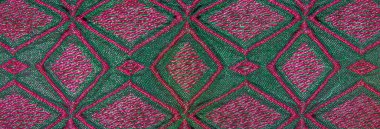 Pembeyle karışık geometrik desenlere sahip canlı yeşil kumaş bulanık yakın plan, zengin dokular ve dinamik kıvrımlar, soyut tekstil tasarımları için mükemmel..