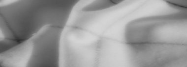 Gri tonlu kumaşın yumuşak kıvrımları ince gölgeler ve renklerle hassas bir doku oluşturarak soyut ve rahatlatıcı bir görsel kompozisyon oluşturur..