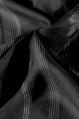 Yumuşak çizgiler ve çiçekli renklerle modern dokuyu klasik tek renkli tonlarla harmanlayan siyah kumaşın karmaşık desenlerini bulanıklaştırır.