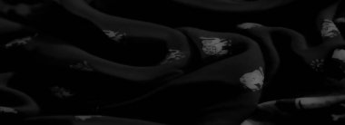 Katlanmış gri tonlu kumaş ve karmaşık soyut desenler. Yumuşak doku ve nazik girdaplar sanatsal ve sofistike bir görünüm yaratır.