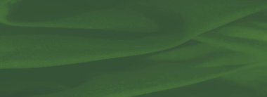 Yumuşak kıvrımları ve kıvrımları olan yeşil kumaş bulanıklığı. Tasarım, maddenin sıvı dokusunun zenginliğini ve zarafetini vurguluyor..