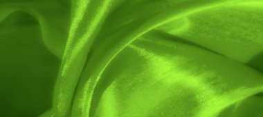 Şeffaf dokuları ve yumuşak dalgalarıyla akan yeşil kumaş bulanıklığı, tekstil tasarımı ve yaratıcı arka planlar için rahatlatıcı ve sanatsal bir estetik oluşturuyor..