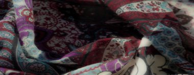 Koyu geometrik dokulara sahip bulanık bir kumaş ve beyaz çiçek aksanları, akışkan kıvrımlarla yumuşatılmış ve sanatsal bir dokunuş için ince mavi ve mor renklerle zenginleştirilmiş..