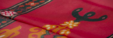 Karmaşık turuncu çiçek desenleri ve parıldayan aksanlarla bezenmiş parlak kırmızı kumaş, tekstil tasarımları ve el sanatları için mükemmel..