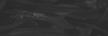 Bulanık siyah kumaş, ince parlak aksanlı düğümlü dokular, derinlik ve entelektüellik havasını estetiğe ekliyor..