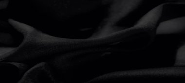 Pahalı ve sanatsal bir görsel cazibe için yumuşak ışıkla vurgulanmış, doğal kıvrımları ve pürüzsüz dokusu olan bulanık siyah kumaş..
