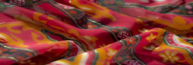 Görüntü, altın çiçekli ve koyu yeşil kenarlı kırmızı kumaşın zarafetini vurgular. Karmaşık desenler ve tasarım için mükemmel yumuşak dokular sergiler.