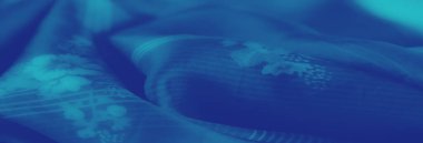 Açık mavi kumaşlı, karmaşık çiçek desenli ve çizgili detaylarla. Akan doku zarafeti yakalar, yumuşak hatlar ve incelikli sanatla..