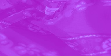 Görüntü. Moda ve dekoratif amaçlar için sanatsal ama işlevsel bir unsur sunan, çiçekli ve soyut desenlerle iç içe süslü, mor bir kumaş..