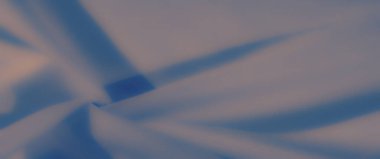 Bulanık, mavi kumaşın zarif kıvrımları, ışık ve gölgeyle hafifçe harmanlanarak, sofistike ve modern basitliğe ışık saçan sakin ve sanatsal bir kompozisyon oluşturuyor..