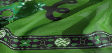 Geometrik mor ve beyaz tasarımlar içeren lüks yeşil kumaş bulanıklığı, yumuşak dokular ve ince bir aura ve incelik saçan ince kenarlar..