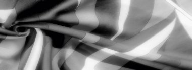 Gri tonlu kumaşın karmaşık kıvrımları büyüleyici bir ışık ve karanlık dansı sahnenin derinliğini ve dokusunu ekliyor. Kumaşlar zarif bir sükunet hissi uyandırıyor.