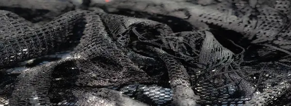 Karmaşık siyah dantel kumaşın bulanık yakın çekimi ışıl ışıl parlak ışıklar ve hassas dokular, zarafet ve sanatsal karmaşıklık hissi yaratıyor..