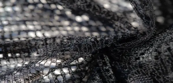 Işıldayan yansımaları ve ızgara gibi bir dokusu olan karmaşık siyah örgü kumaşı. Herhangi bir tekstil projesine zarafet ve derinlik eklemek için mükemmel.