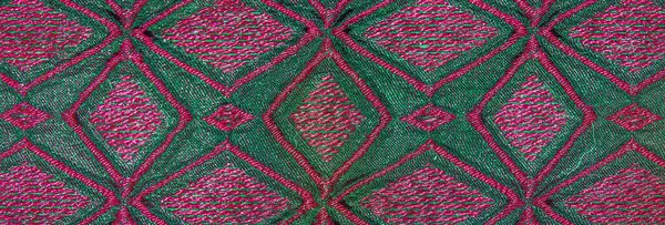 Pembeyle karışık geometrik desenlere sahip canlı yeşil kumaş bulanık yakın plan, zengin dokular ve dinamik kıvrımlar, soyut tekstil tasarımları için mükemmel..