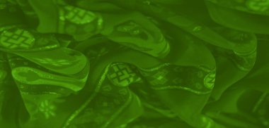 Karmaşık desenli, parlak parıltılı yeşil kumaşın bulanık görüntüsü canlı ve dokulu bir görünüm yaratıyor..